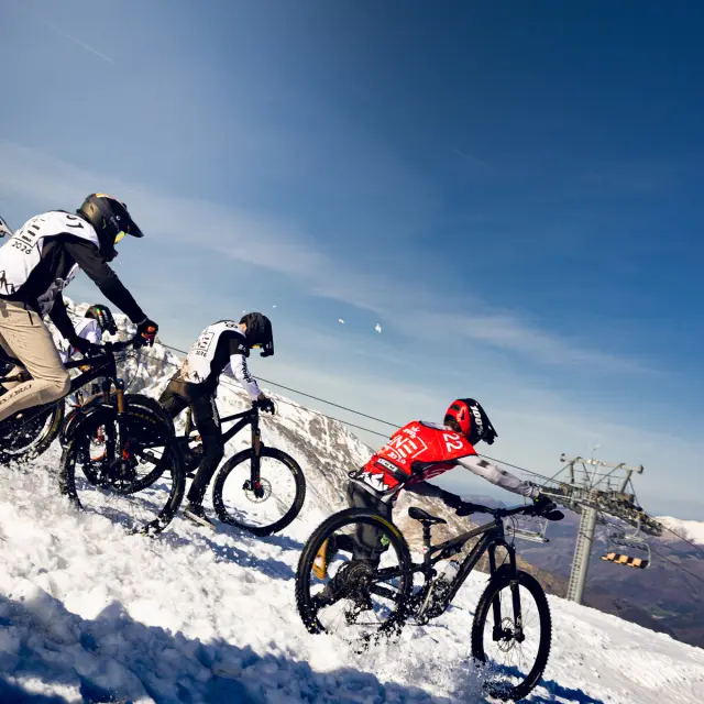 Vététistes participant à une descente VTT sur neige lors de l'Evo2 Line à Saint-Lary-Soulan.