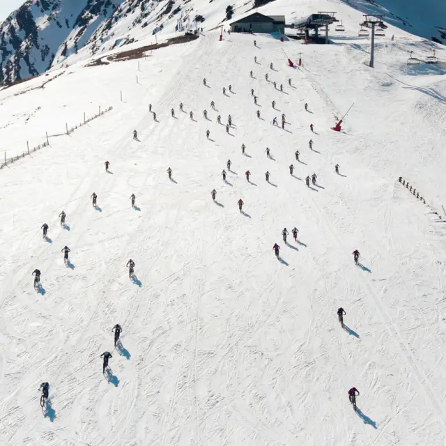 Participants à une course de VTT sur neige évoluant sur un plateau enneigé à Saint-Lary-Soulan